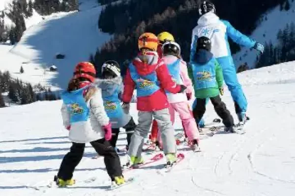 Un gruppo di bambini prende lezioni di sci su una pista innevata.