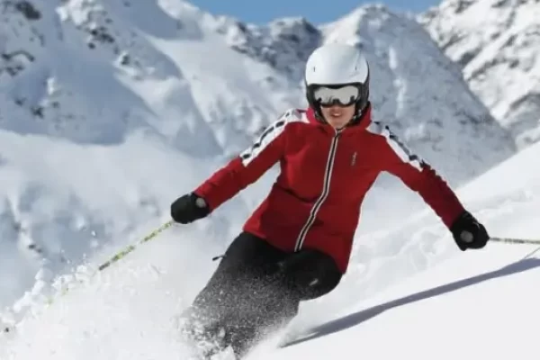Persona che scia in montagna con abbigliamento da sci rosso.