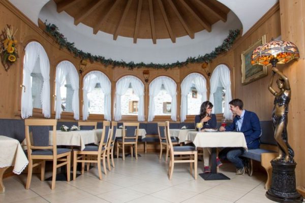 Due persone sedute a un tavolo in un'accogliente sala da pranzo con arredi in legno e decorazioni floreali.